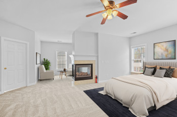 Carpeted bedroom featuring ceiling fan and a multi sided fireplace