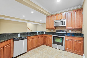 Kitchen with appliances with stainless steel finishes, sink, dark stone counters, and light tile flooring