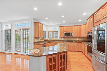 Kitchen with appliances with stainless steel finishes, a kitchen island, light wood-type flooring, and dark stone countertops