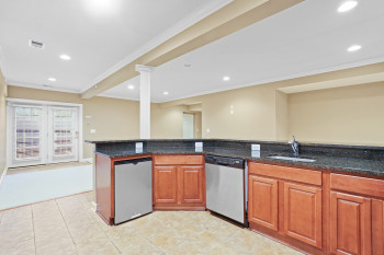 Kitchen featuring sink, dark stone countertops, ornate columns, and stainless steel dishwasher