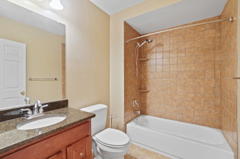 Full bathroom with tile flooring, oversized vanity, tiled shower / bath combo, and toilet