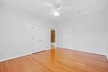 Unfurnished bedroom with light hardwood / wood-style flooring, ceiling fan, and ensuite bath