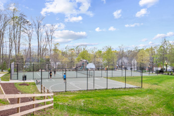 View of tennis court featuring basketball court and a lawn