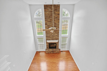 Unfurnished living room featuring plenty of natural light, light hardwood / wood-style floors, a stone fireplace, and ceiling fan