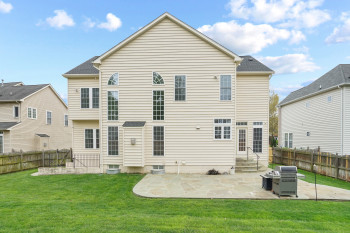 Rear view of property with a patio area, central air condition unit, and a lawn