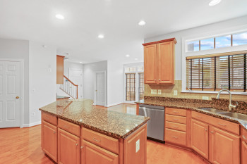 Kitchen featuring a kitchen island, stone counters, dishwasher, and light wood-type flooring