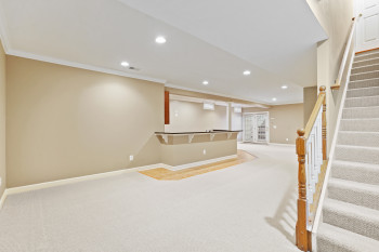 Basement featuring ornamental molding and light colored carpet