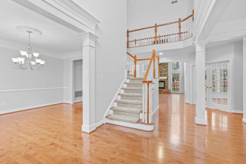 Stairway featuring a notable chandelier, light hardwood / wood-style floors, and decorative columns