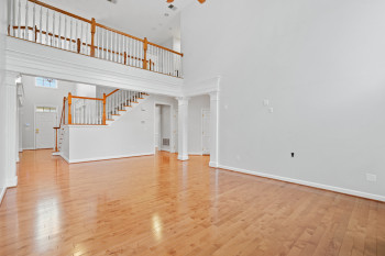 Unfurnished living room featuring light hardwood / wood-style flooring, decorative columns, and a towering ceiling