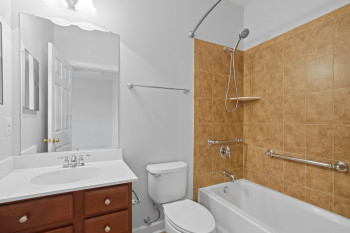 Full bathroom featuring tiled shower / bath, vanity with extensive cabinet space, and toilet