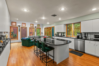 Kitchen with stainless steel dishwasher, a kitchen bar, white cabinetry, light wood finished floors, and recessed lighting