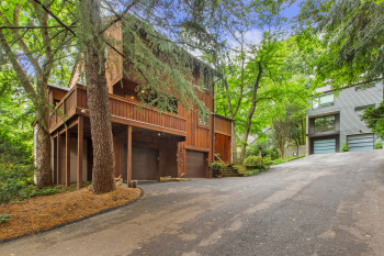 View of front facade with an attached garage, driveway, and a wooden deck