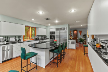 Kitchen featuring appliances with stainless steel finishes, a breakfast bar, modern cabinets, white cabinetry, and dark countertops