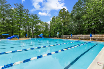 Community pool featuring a water slide and view of scattered trees
