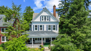 View of front facade featuring a chimney and covered porch