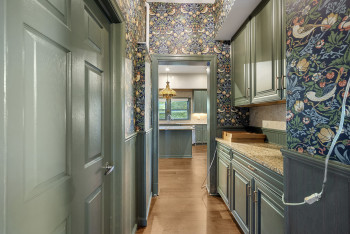 Kitchen featuring wallpapered walls, a wainscoted wall, and wood finished floors