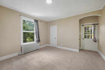 Unfurnished room featuring radiator heating unit, crown molding, carpet flooring, and arched walkways