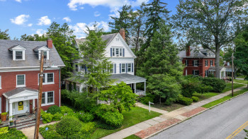 View of front of home with a chimney, a high end roof, and brick siding