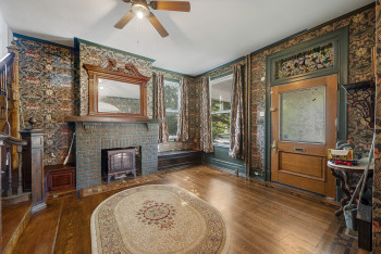 Living area featuring wood finished floors, a ceiling fan, wallpapered walls, and ornamental molding