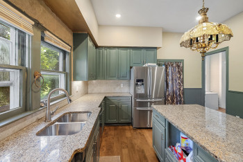 Kitchen featuring stainless steel refrigerator with ice dispenser, light stone counters, dark wood-type flooring, hanging light fixtures, and recessed lighting