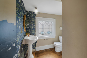 Half bathroom with wood finished floors and wallpapered walls