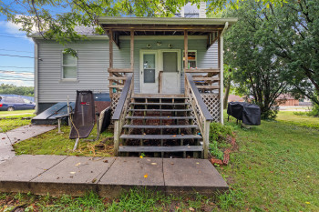 View of front facade with a chimney, a front yard, and covered porch