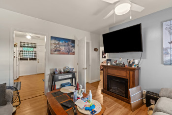 Living area featuring a ceiling fan, light wood-style flooring, and a fireplace