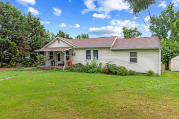Ranch-style house with a storage unit, covered porch, and a front yard