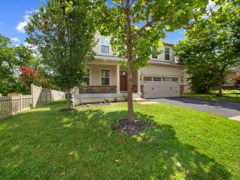 Obstructed view of property featuring an attached garage, driveway, and a porch