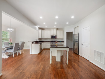Kitchen with recessed lighting, a kitchen breakfast bar, dark wood-style floors, white cabinetry, and appliances with stainless steel finishes