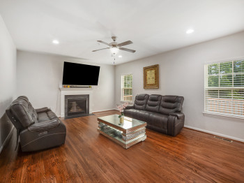 Living room with wood finished floors, recessed lighting, a fireplace with flush hearth, and a ceiling fan