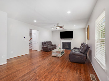 Living area with wood finished floors, a glass covered fireplace, ceiling fan, and recessed lighting
