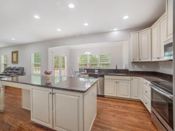 Kitchen with stainless steel appliances, recessed lighting, a kitchen island, wood finished floors, and white cabinets