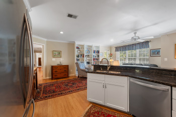 Kitchen featuring stainless steel appliances, white cabinetry, dark stone counters, light wood-type flooring, and ornamental molding