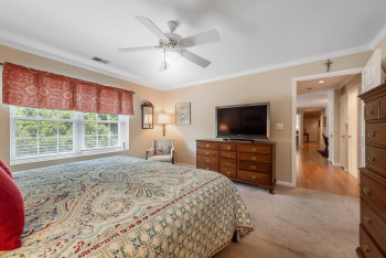 Bedroom with ornamental molding, light colored carpet, and ceiling fan