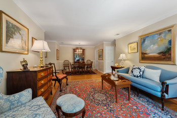 Living room featuring light wood-style floors, ornamental molding, and a chandelier