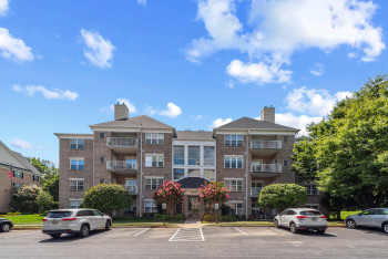 View of apartment building / complex featuring uncovered parking