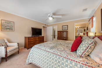 Bedroom with crown molding, light colored carpet, a ceiling fan, and ensuite bath