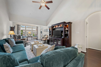 Living area with high vaulted ceiling, dark wood-style flooring, a ceiling fan, and arched walkways