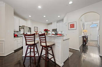 Kitchen with a breakfast bar, white cabinets, tasteful backsplash, arched walkways, and light stone countertops