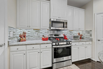 Kitchen with white cabinets, appliances with stainless steel finishes, and light stone countertops