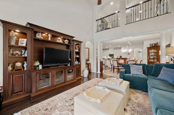 Living area featuring dark wood-type flooring, arched walkways, a chandelier, a towering ceiling, and recessed lighting