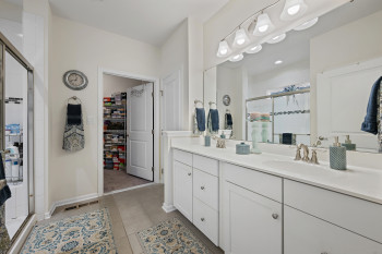 Primary En Suite  Bathroom featuring a stall shower, double vanity, a spacious closet, and light tile patterned floors
