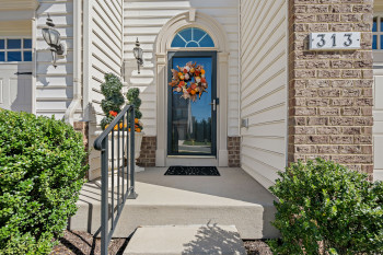 View of lovely set back main entry with brick work and Charleston style siding and porch