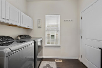 Washroom with dark wood-style flooring, washing machine and clothes dryer, and cabinet space