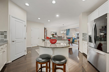 Kitchen with decorative backsplash, white cabinets, stainless steel refrigerator with ice dispenser, a kitchen island with sink, and a breakfast bar