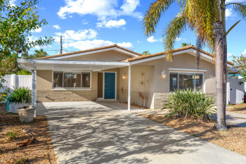 View of front facade with stucco siding, brick siding, and a tile roof