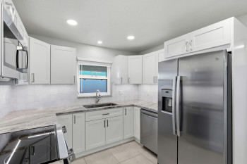 Kitchen with stainless steel appliances, light Quartz countertops, white shaker cabinetry, light tile patterned floors, and recessed lighting