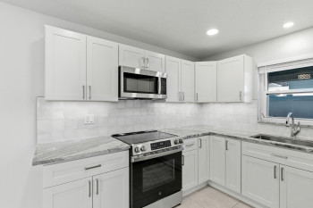 Kitchen with stainless steel appliances, light Quartz countertops, white shaker cabinetry, light tile patterned floors, and recessed lighting