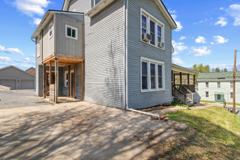 View of property exterior featuring a garage, a lawn, and an outbuilding
